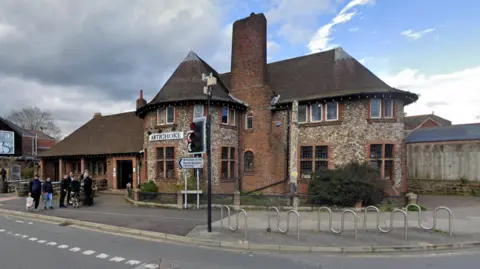 Google Google street view image of the Artichoke pub where people are stood outside and walking past. 