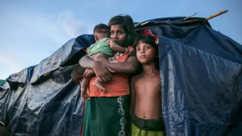 Getty Images A Rohingya refugee family stands by their makeshift home in Bangladesh