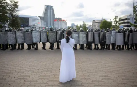 Reuters Woman in white facing line of riot police