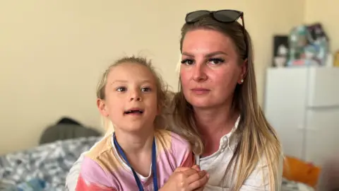 Kinga and daughter Victoria sat on a bed
