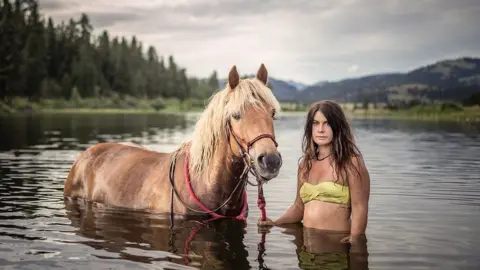 Jessica stands in water with her horse