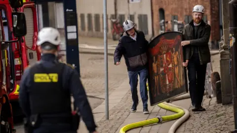 Getty Images Mr Mikkelsen and a colleague carry an ornate historic painting