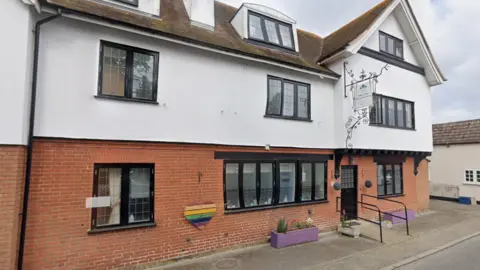 Google A view of the white building where the care home is based. It has black window frames and a sign hanging above the black door with the name of the home.