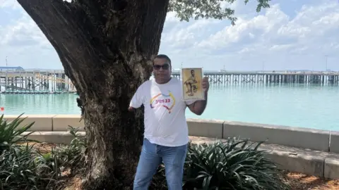 Richard Fejo holding a picture of his relative Samuel Fejo