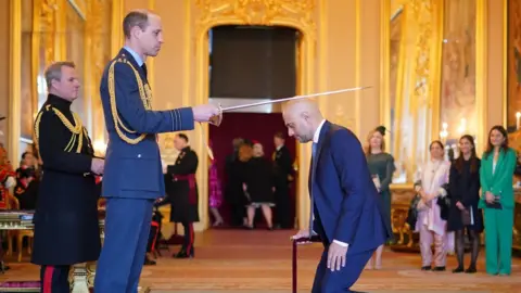 PA Media Sir Sajid Javid bends down before Prince William to receive his knighthood