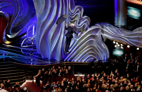 AFP Keegan Michael Key comes down from the roof with an umbrella