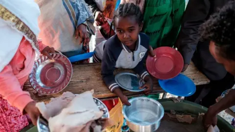 AFP A displaced child from Western Tigray waits at meal time to receive a plate of food outside a classroom in the school where they are sheltering in Tigray's capital Mekele on February 24, 2021.