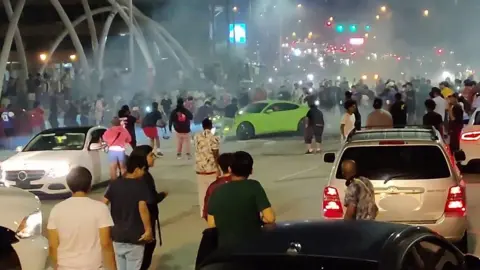 A screengrab from footage shows a stunt driver blocking an overpass in Atlanta, while pedestrians watch