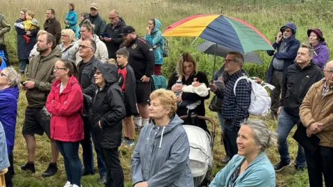 A group of people standing in the rain in a field