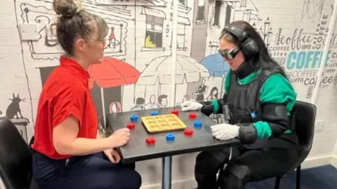 Brunel Care An employee playing a board game whilst wearing the suit