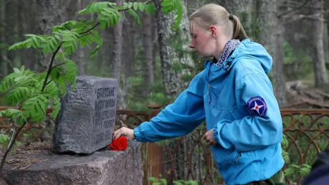 Marina Titova lays a carnation on a grave stone on Mudyug Island