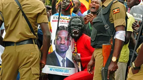 AFP Bobi Wine supporters pose with his poster