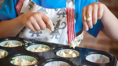 Getty Images Child baking cupcakes