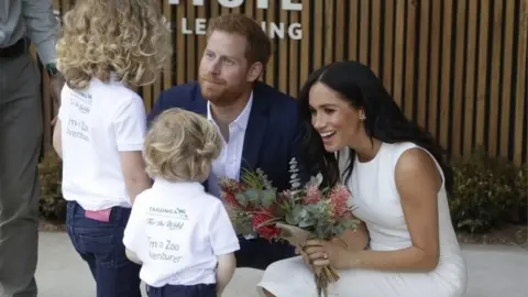 PA The Duke and Duchess of Sussex receive native flowers from Finley Blue and Dasha Gallagher at Taronga Zoo in Sydney, Australia