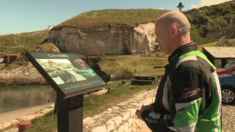 A man reading a Game of Thrones sign at Ballintoy Harbour