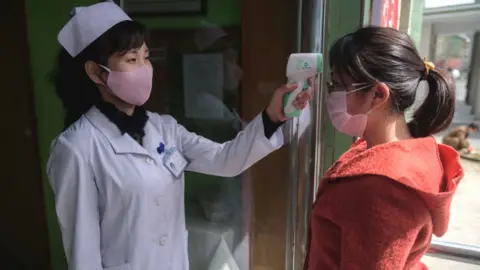 Getty Images A health worker takes the temperature of a woman