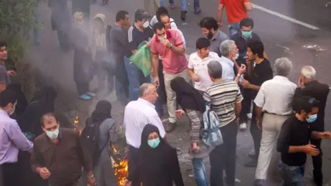 Getty Images Protesters gathering during the 2009 protest, with some individuals blowing smoke into each other's eyes to lessen the impact of tear gas.