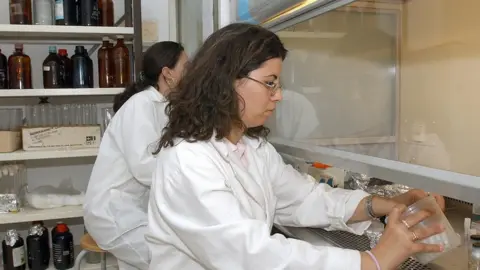 AFP Two women handle chemicals behind a protective screen in a lab in Tunis.