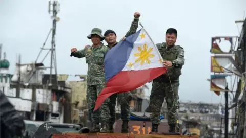 AFP Philippine soldiers aboard their armoured personnel carrier celebrate after President Rodrigo Duterte declared Marawi City "liberated", inside the battle area of Bangolo in Marawi on October 17, 2017.