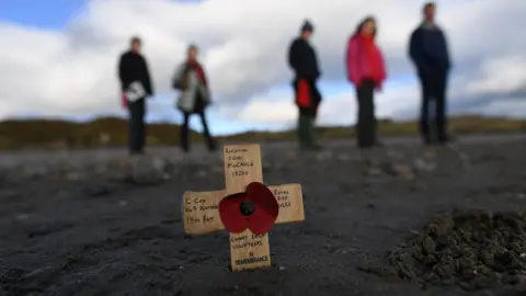 Reuters A remembrance cross is planted in the sand as volunteers draw depictions of those killed in World War One, part of Danny Boyle's Pages of The Sea celebrations, on Murlough Beach in Newcastle, Northern Ireland.