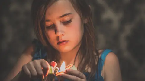 Getty Images Girl lights candle