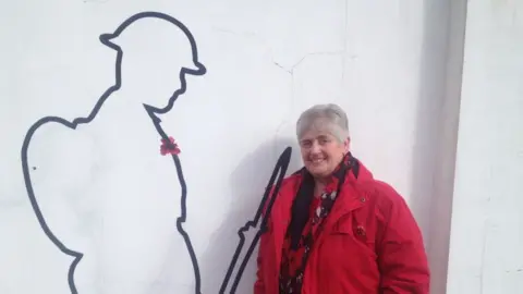 Lynda Osborne, standing with a WWI statue at Big Pit Coal National Coal Museum