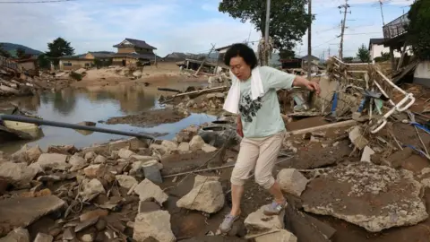 AFP A resident walks across scattered debris in a flood hit area in Kurashiki, Okayama prefecture on July 9, 2018.