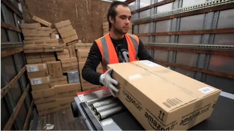 Getty Images An Amazon worker loads a package on a truck