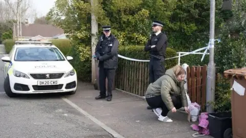 PA Media Woman lays flowers outside a house