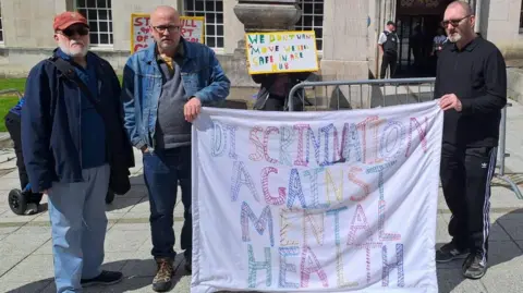 A group of four protesters with handwritten signs stood outside Leeds Civic Hall 