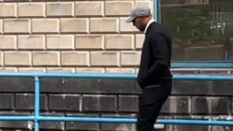 PA Former firefighter Cameron Hancel leaving Wolverhampton Crown Court wearing a baseball cap following the hearing