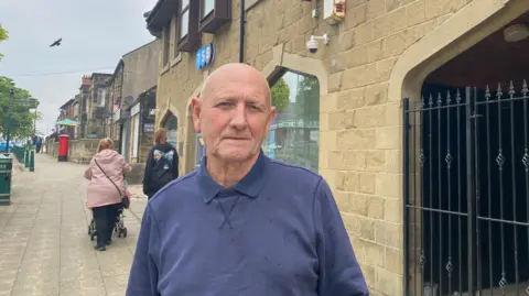 A picture of James Bell standing outside the TSB branch in Bedlington