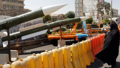 Getty Images A woman looks at missiles on display during a street exhibition in Tehran, Iran