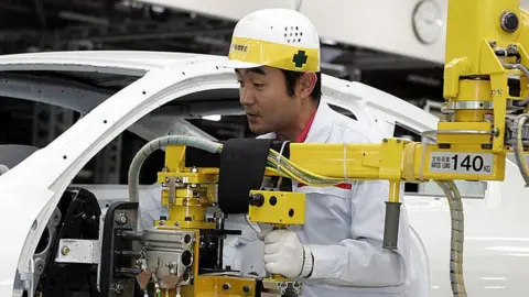 Getty Images Nissan worker on assembly line.