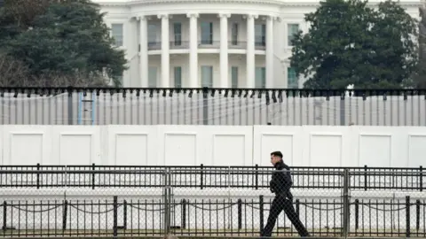 Reuters A member of the Secret Service walks along security fence installed around the White House