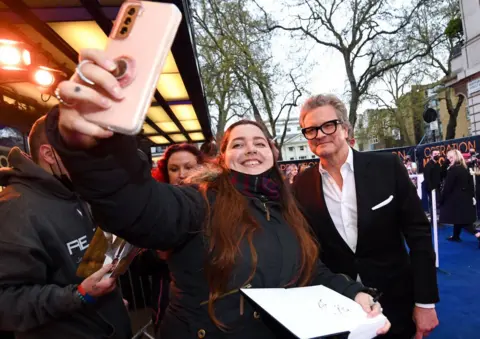 Jeff Spicer / Getty Images for Warner Bros. Colin Firth takes a selfie with a fan
