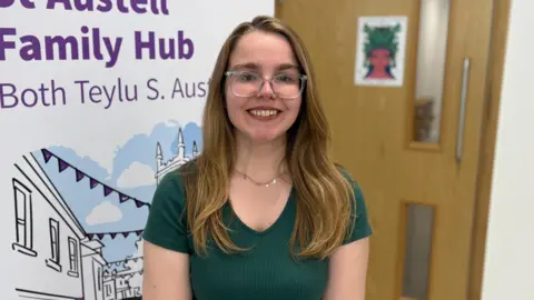 BBC Charlotte Allen-Squire has long light brown hair down past her shoulders and wears glasses and a dark black top. 