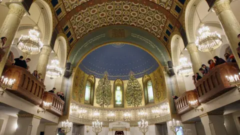 Getty Images The interior of the Moscow Choral Synagogue shows a magnificent domed ceiling lit with candles and elaborately decorated.