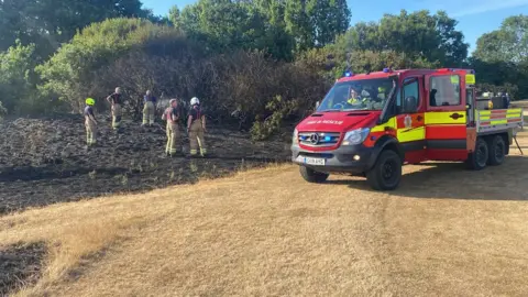 Essex County Fire and Rescue Service Firefighters inspect the scene of a fire on grassland in Southend