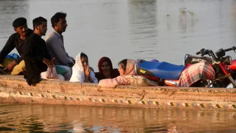 Getty Images People crowded together on a boat in a flooded area in Pakistan