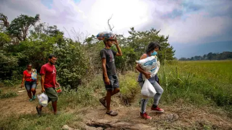 AFP Venezuelan citizens cross from Cucuta in Colombia back to San Antonio del Tachira in Venezuelavia an illegal trail on the border between the two countries