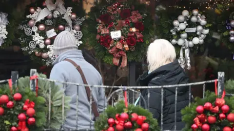 PA Media people looking at Christmas wreaths