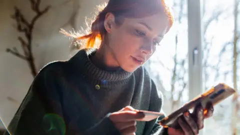 Getty Images Woman making a payment with her card on her smartphone