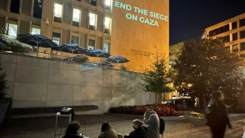 @lily1sabella Slogans beamed on to side of library at GW University on 24 October 2023