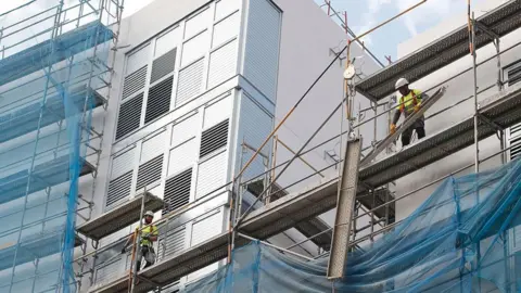 Getty Images Worker disassemble scaffolding built along the facade of a building under construction in Barcelona