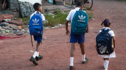 Ishara Danasekara/BBC Children walking to school with bags on their back