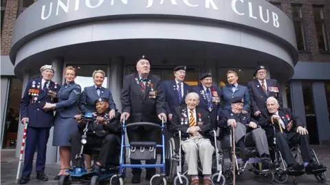 PA Media D-Day and Normandy veterans (left to right) Alec Penstone, 98, Gilbert Clarke, 98, Richard Aldred, 99, Henry Rice, 98, Donald Howkins, 103, Mervyn Kersh, 98, Stan Ford, 98, Ken Hay, 98, and John Dennett, 99, with the D-Day Darlings at the D-Day 80 launch event organised by the Spirit of Normandy Trust, in conjunction with the British Normandy Memorial, at the Union Jack Club in London.