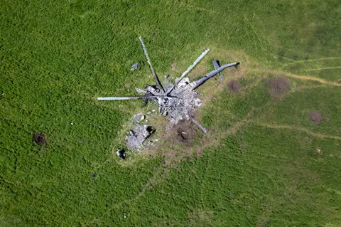 John Moore / Getty Images The remains of a Russian helicopter lie in a bomb-cratered field in Biskvitne, Ukraine to the east of Kharkiv