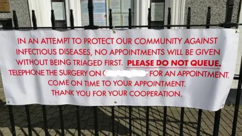 This sign has appeared in front of a surgery in Conwy to try to encourage patients to call first