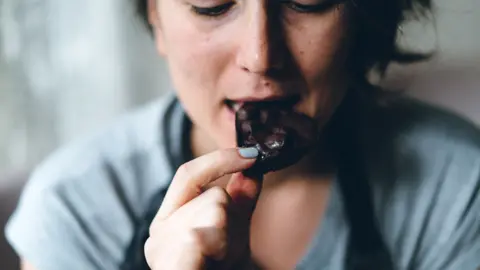Getty Images A woman eats a piece of chocolate
